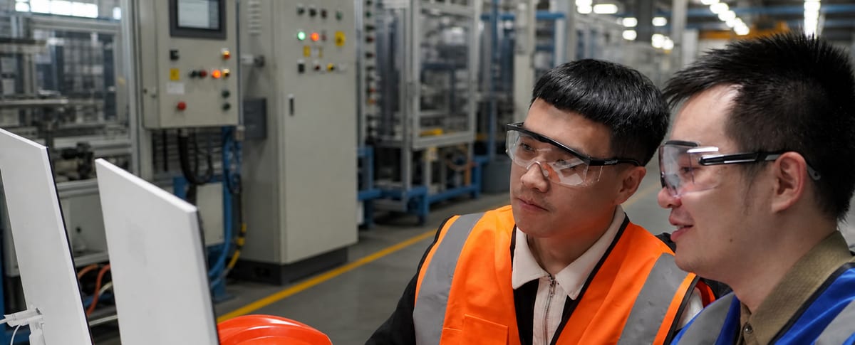 PLC Autocontroller technicians reviewing automation equipment on a factory floor